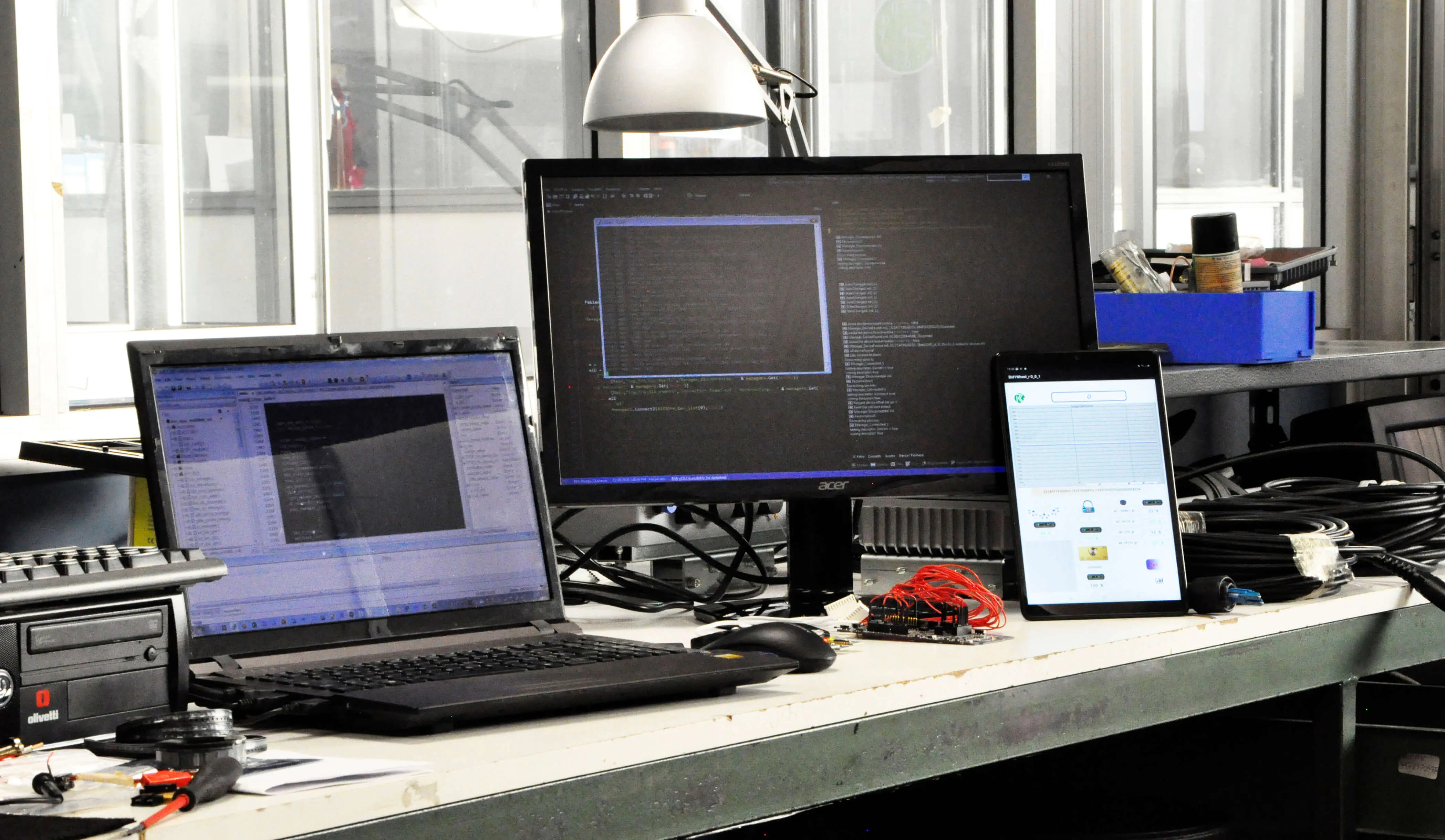 Postazione di sviluppo con layout PCB a schermo e scheda sotto test